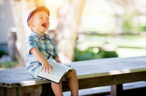 Child reading a book and laughing