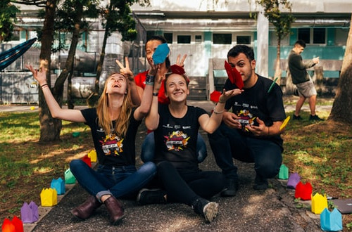 Young adults sitting and throwing origami into the air