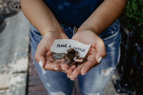 Hands holding money and sign that read 'make a change'